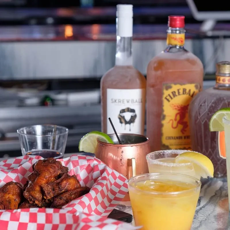 Crispy chicken wings, assorted drinks, and whiskey bottles on a bar counter.