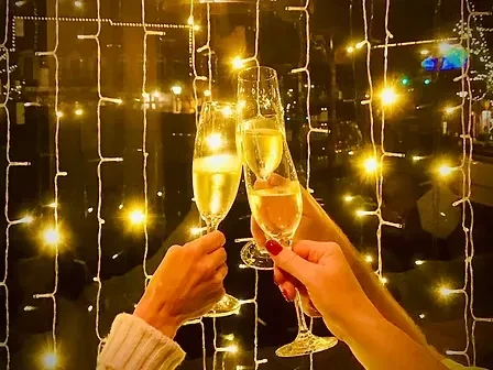 Three hands clinking champagne flutes in a festive toast.
