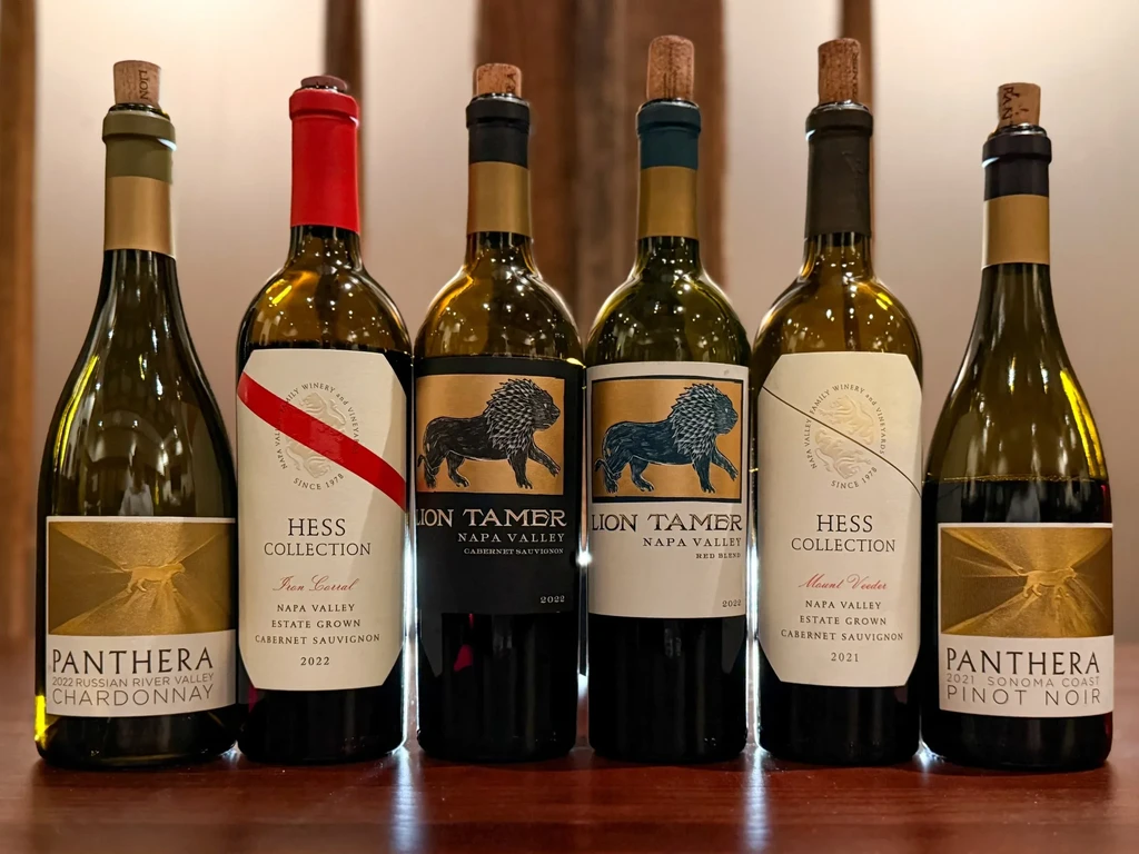 Six wine bottles with unique labels arranged on a wooden surface.