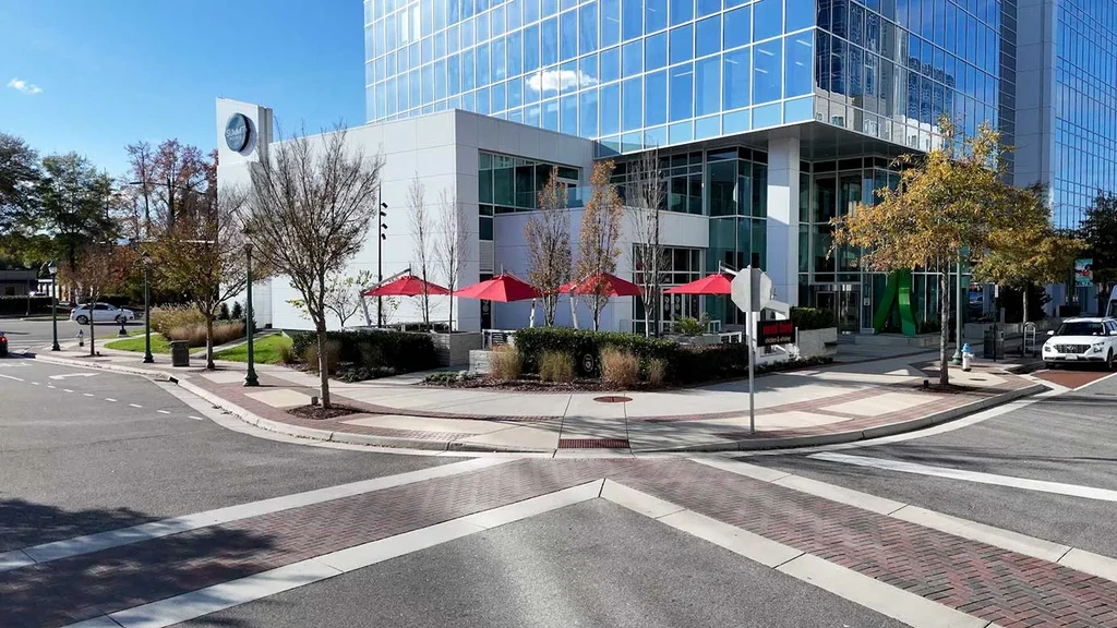 Modern building with 'Great Wraps' restaurant, red umbrellas, and outdoor seating.