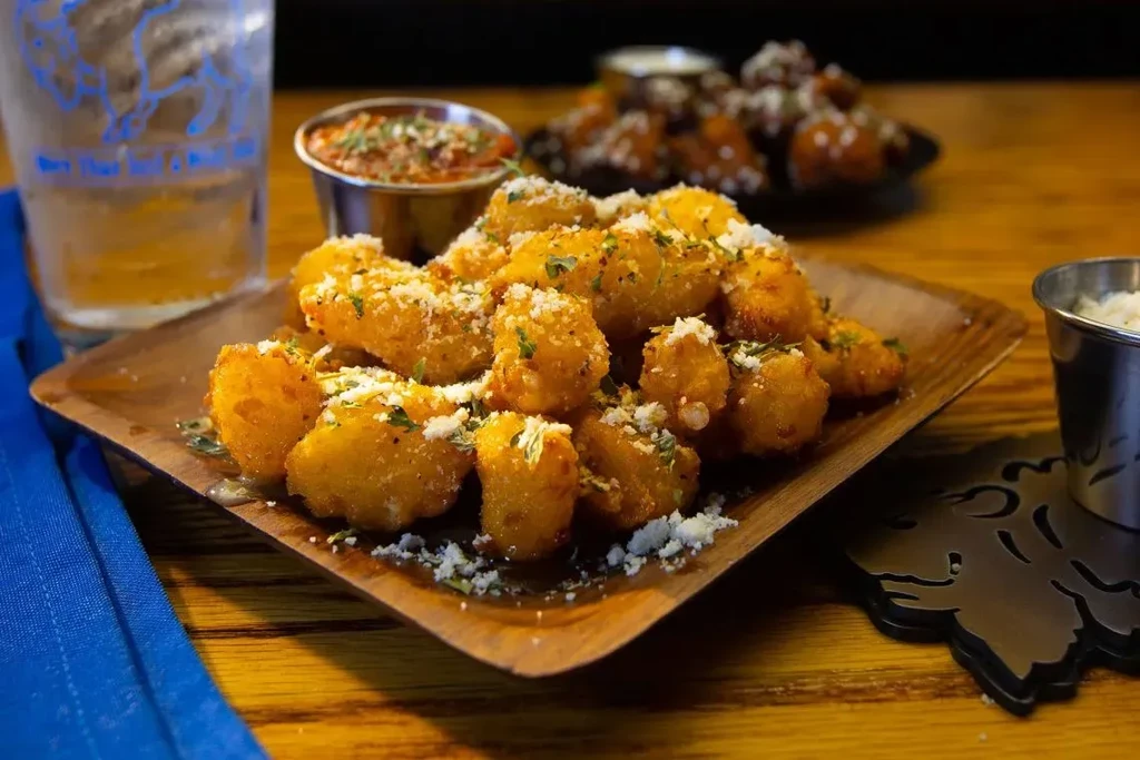 Fried cheese curds, grated cheese, green herbs, and red dipping sauce.