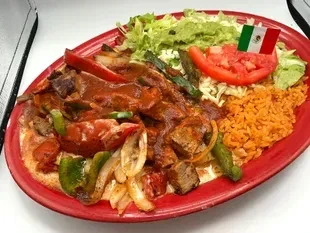Plate of Mexican meat dish with rice, guacamole, and a flag.