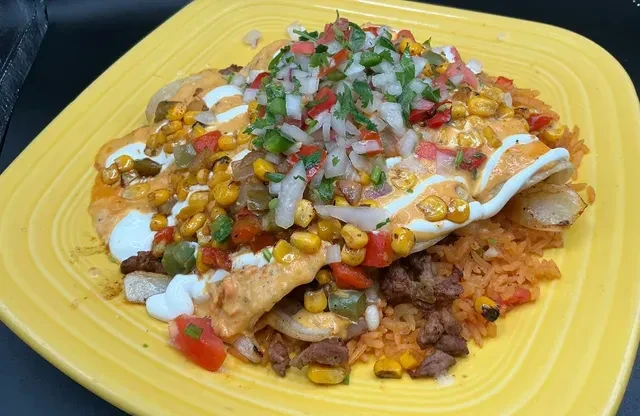 Vibrant Mexican dish with rice, sauced meat, and fresh vegetable salsa.