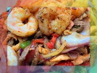 Close-up of seasoned shrimp and meat fajitas with colorful vegetables.