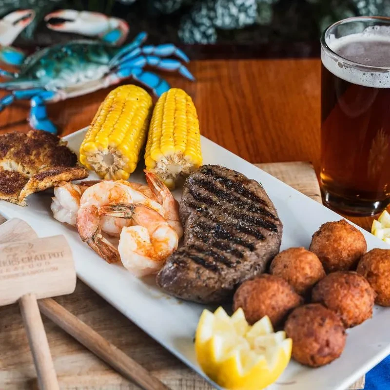 Platter of crab cake, shrimp, steak, corn, hushpuppies, and beer.