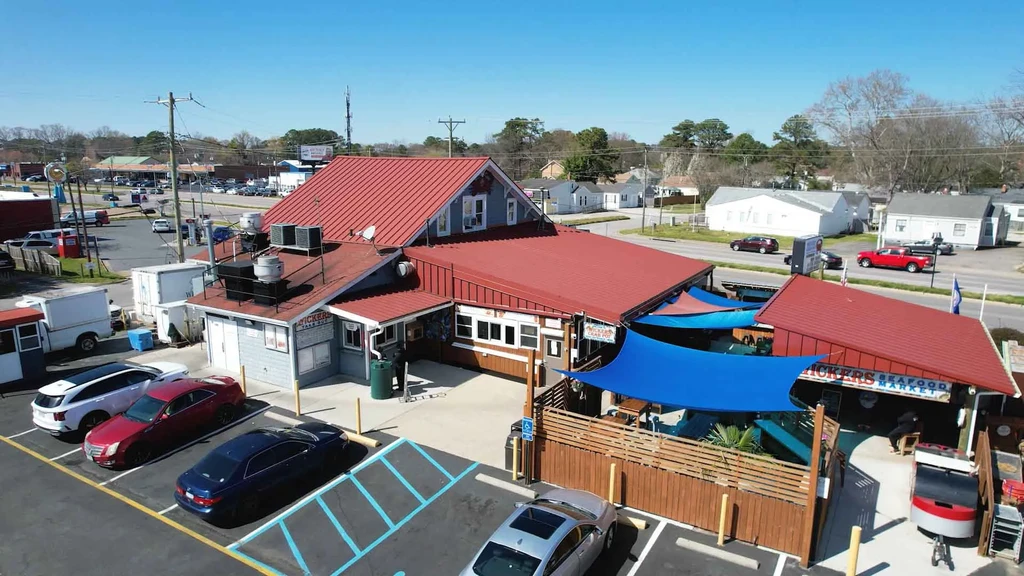 Aerial shot: Red-roofed restaurant, blue shade sails, and outdoor patio.