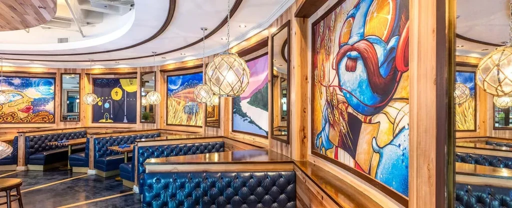 Restaurant interior with blue curved booths, wooden tables, abstract art.