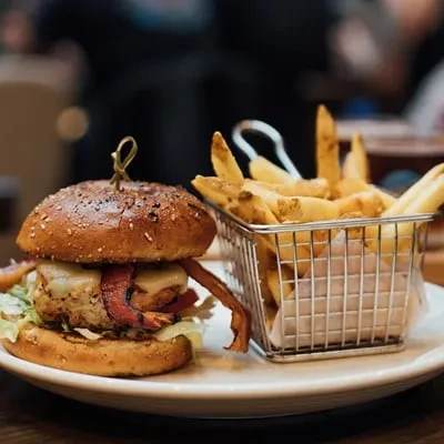 Gourmet burger with bacon, cheese, lettuce, and skin-on french fries.