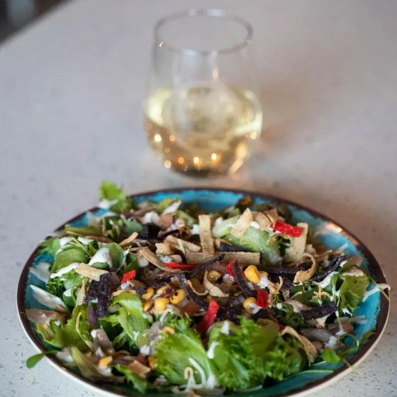 Vibrant salad with corn, bell pepper, tortilla strips, and dressing.