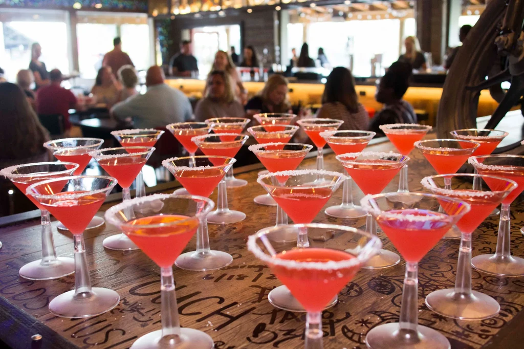 Vibrant red cocktails in sugared martini glasses on a rustic wooden bar.