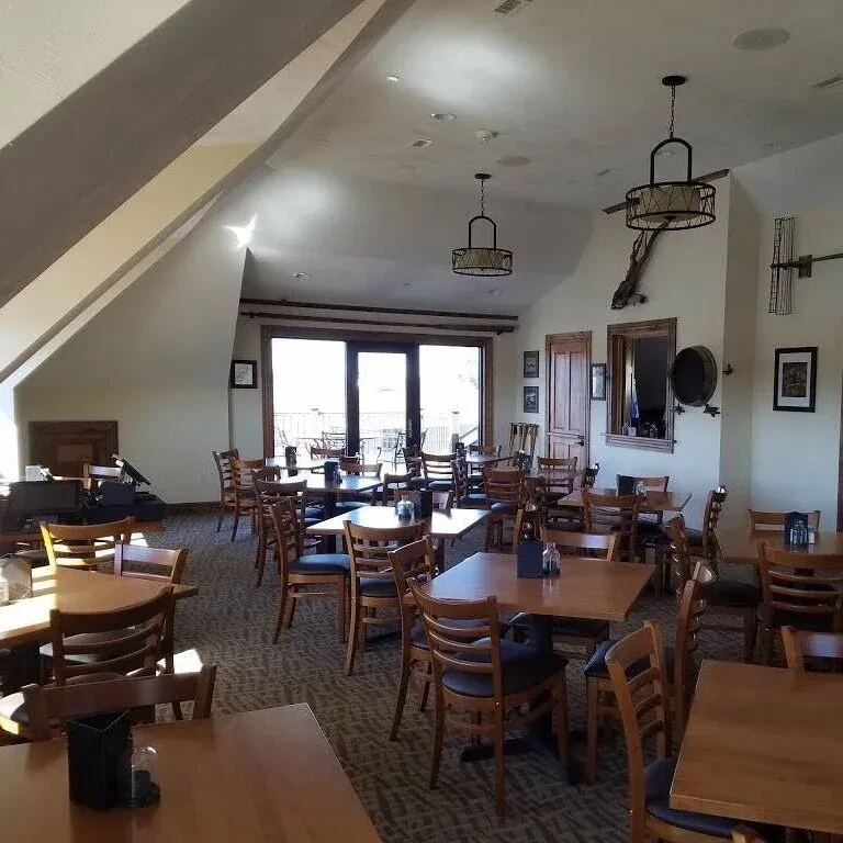 Empty rustic restaurant dining room with wooden tables and unique decor.