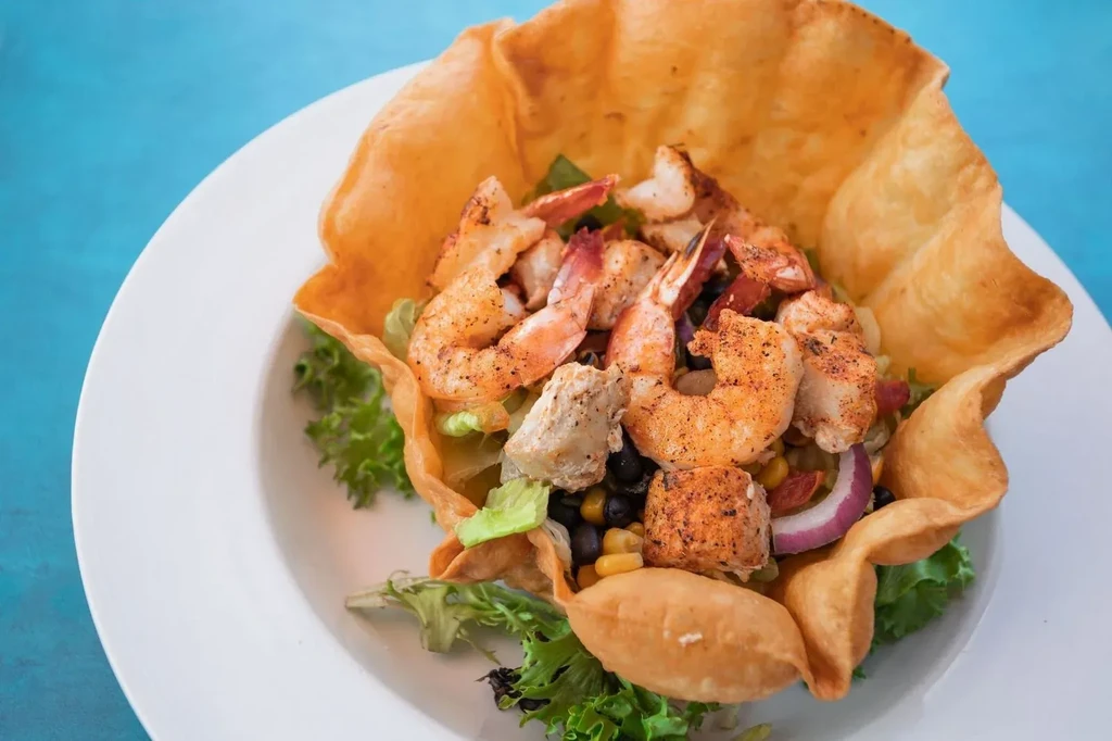 Golden tortilla bowl salad with grilled shrimp, chicken, and beans.