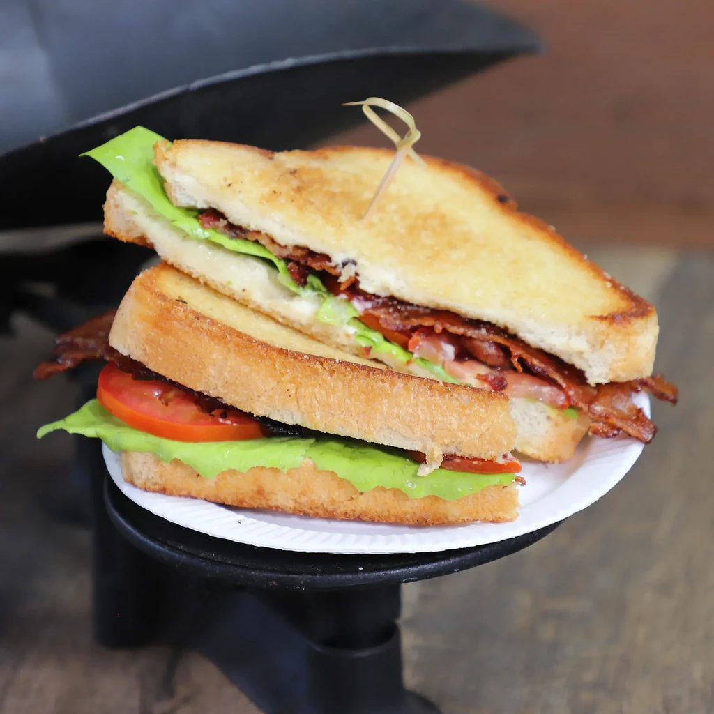 Halved BLT sandwich, well-lit, showing bacon, lettuce, tomato, toasted bread.
