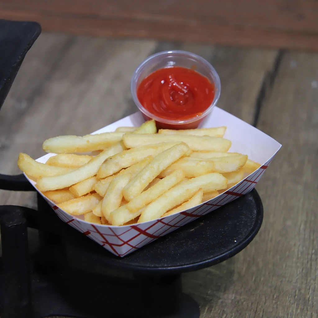 Golden french fries in a tray with a cup of ketchup.