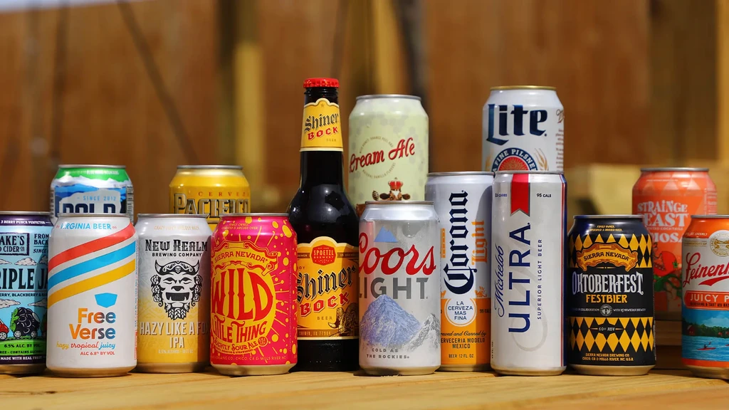 Diverse beer cans and one bottle displayed on a wood surface.