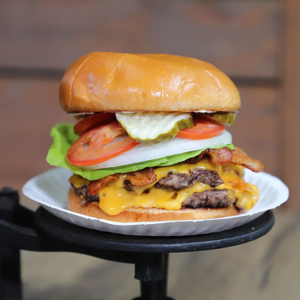 Double cheeseburger stacked with bacon, melted cheese, lettuce, tomato.