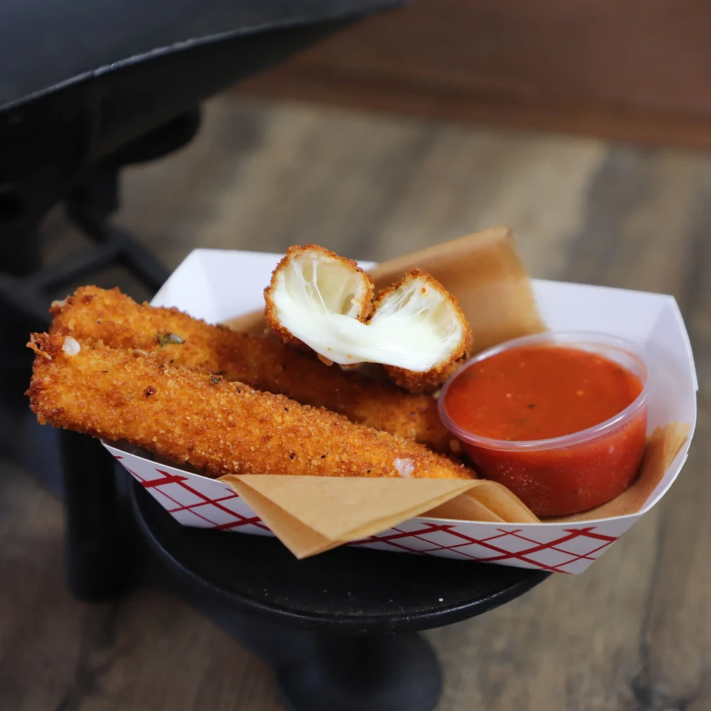Golden mozzarella sticks in a tray, with melted cheese pull and marinara.