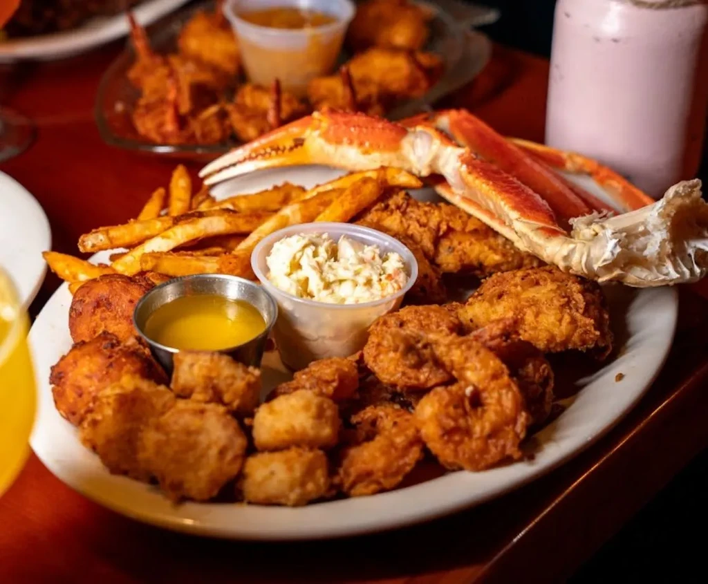 Large plate of fried shrimp, fish, fries, hush puppies, and crab.