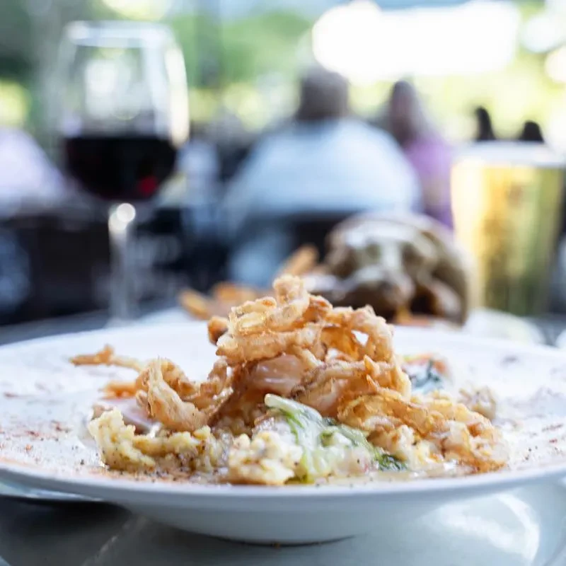 Creamy risotto-like dish with green leaves and crispy fried onions.