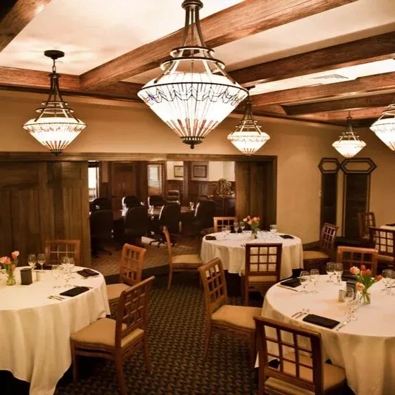Elegant restaurant dining room with set tables, dark wood, and warm lighting.
