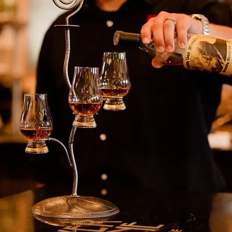 Hand pouring Pappy Van Winkle whiskey into Glencairn glasses.