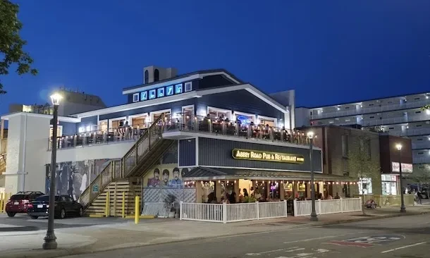 Abbey Road Pub exterior at night, with patrons dining outdoors.