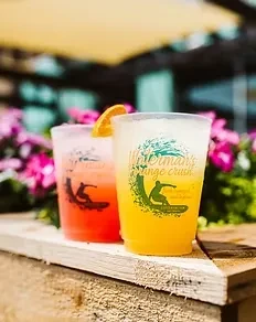 Two colorful Waterman's branded drinks on a wooden outdoor table.