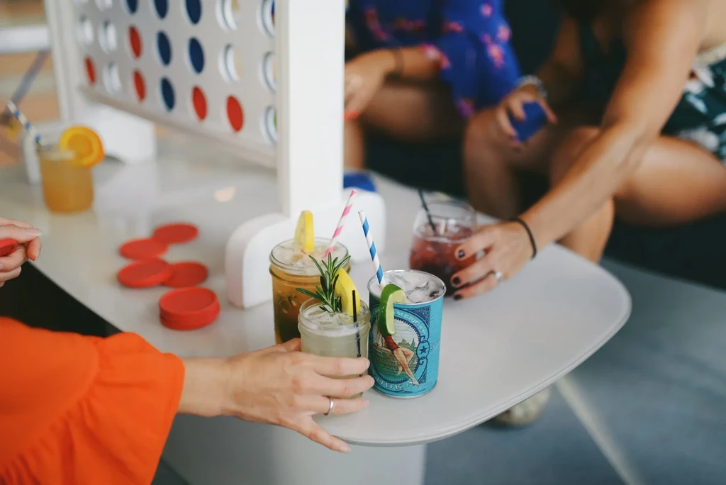 Hands reaching for drinks and a large game board.
