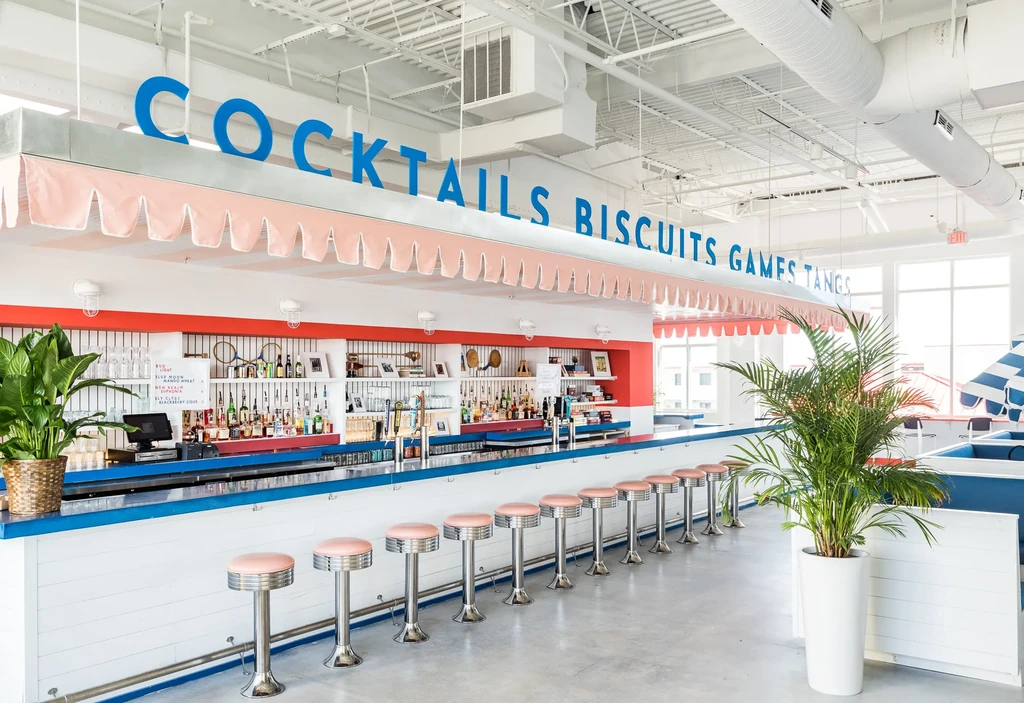 Retro-inspired bar with pink stools, blue trim, and "COCKTAILS" sign.
