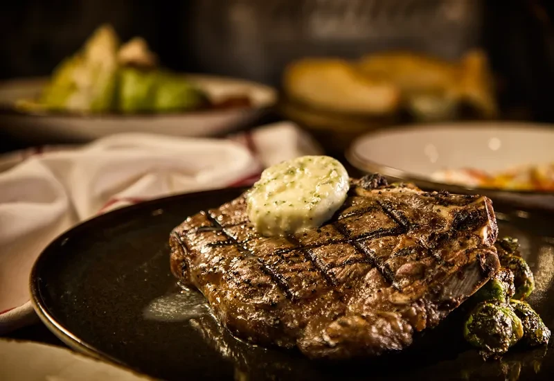Grilled steak with melting herb butter, grill marks, and Brussels sprouts.