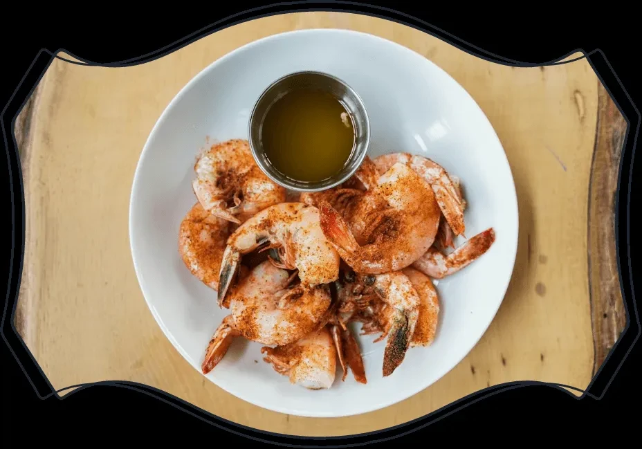 Top-down: Spiced shrimp on white plate with melted butter cup.