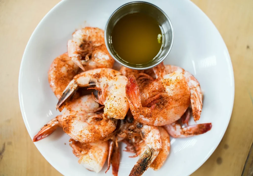 Spiced shrimp and dipping sauce on a white plate.
