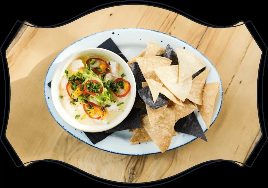 Overhead ceviche bowl with herbs, peppers, and tortilla chips.