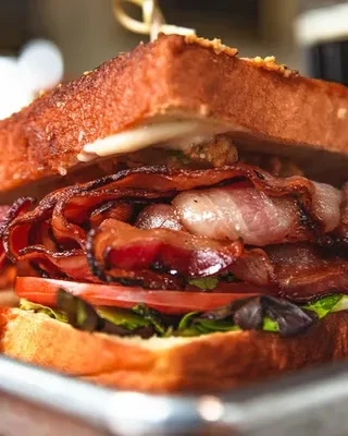 Close-up: Generously filled BLT sandwich with crispy bacon, lettuce, tomato.
