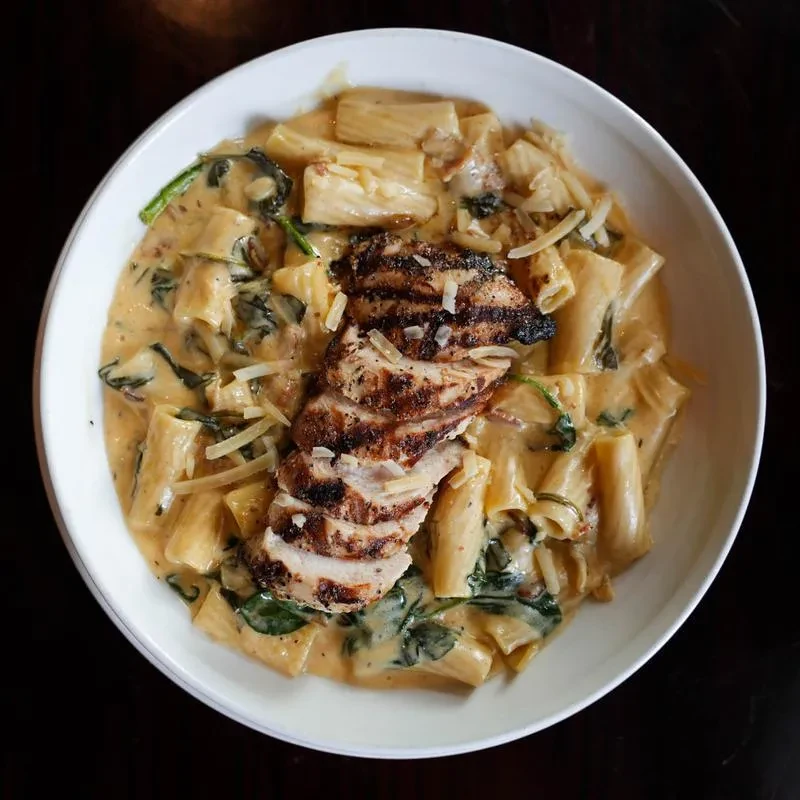 Grilled chicken rigatoni pasta with creamy orange sauce, spinach, and cheese.