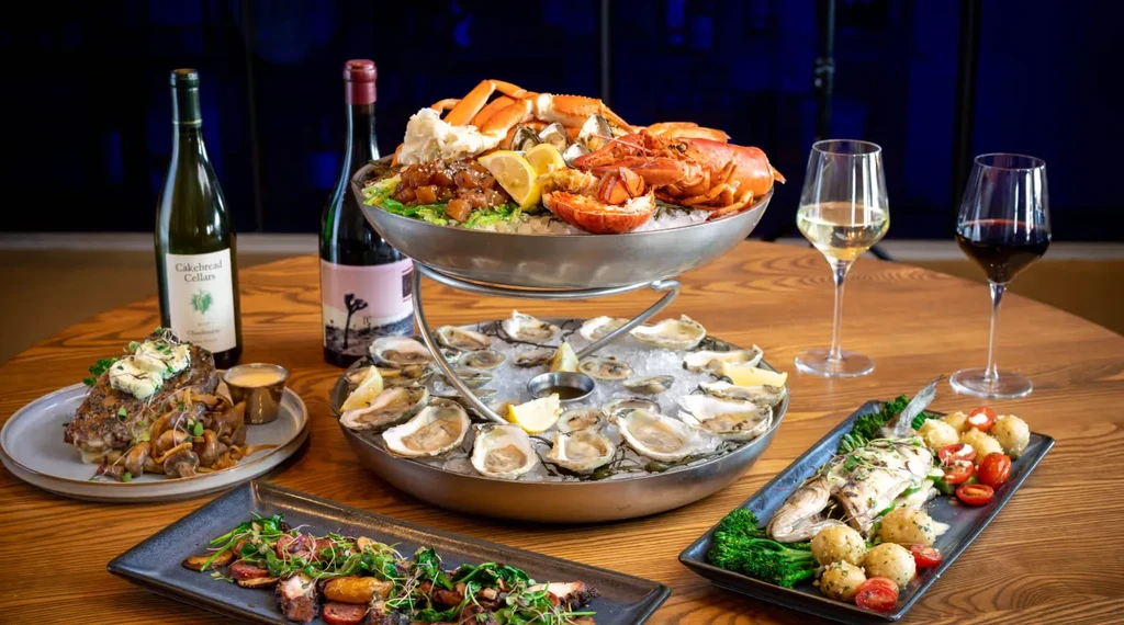 Lavish two-tiered seafood tower with gourmet dishes and wine.