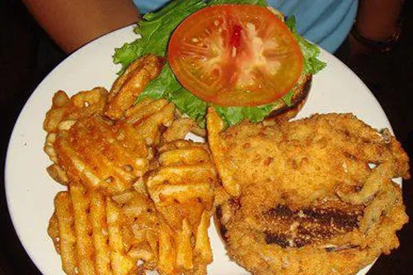 Fried seafood, waffle fries, and burger bun with lettuce on a plate.