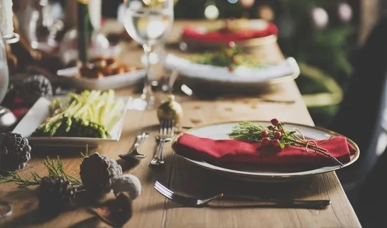 Festive wooden dining table set with plates, napkins, and natural decor.