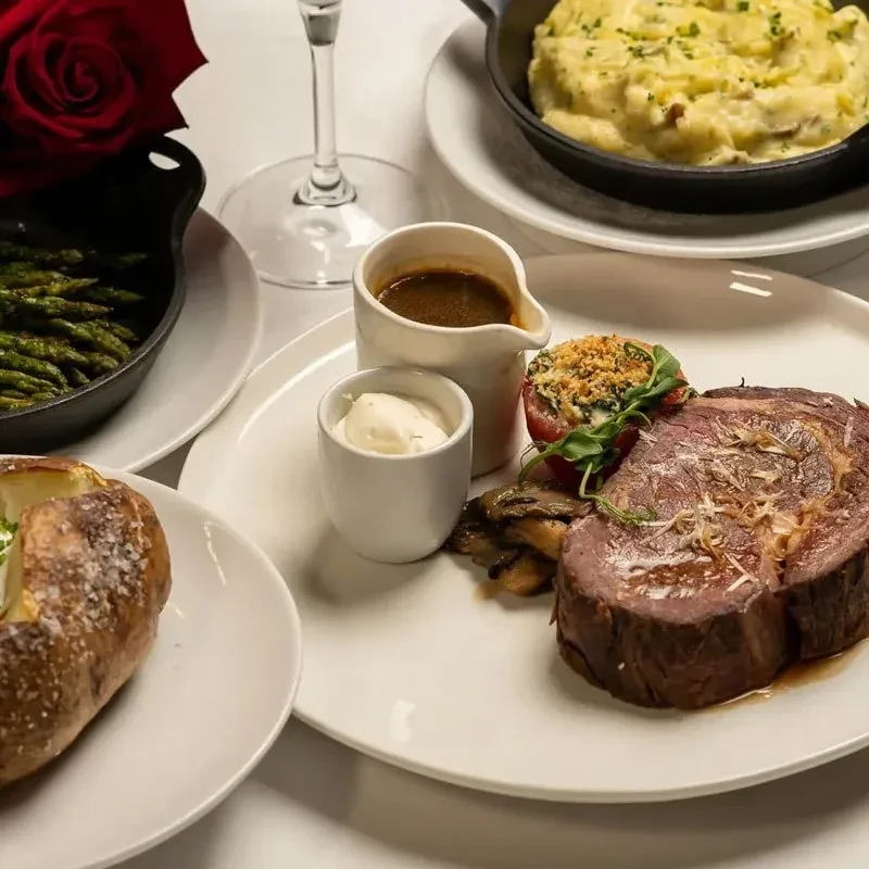 Elegant gourmet dinner featuring roasted meat, potatoes, asparagus, and sauces.