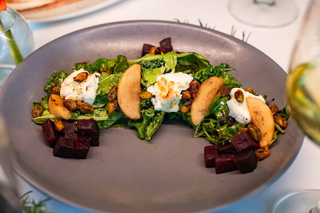 Artfully plated salad: kale, burrata, caramelized pears, pistachios, beetroot.