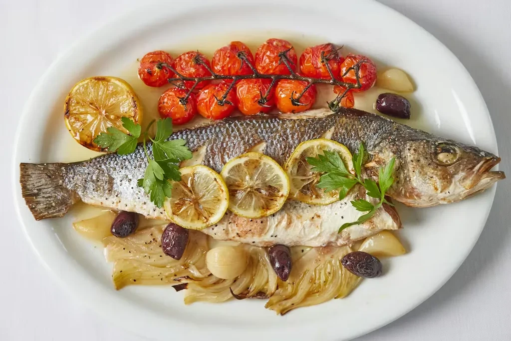 Cooked fish with roasted tomatoes, fennel, garlic, lemon, and olives.