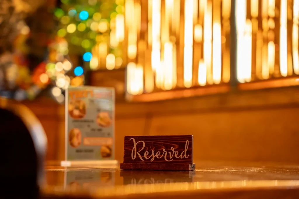A 'Reserved' sign on a wooden table with blurred warm lights.