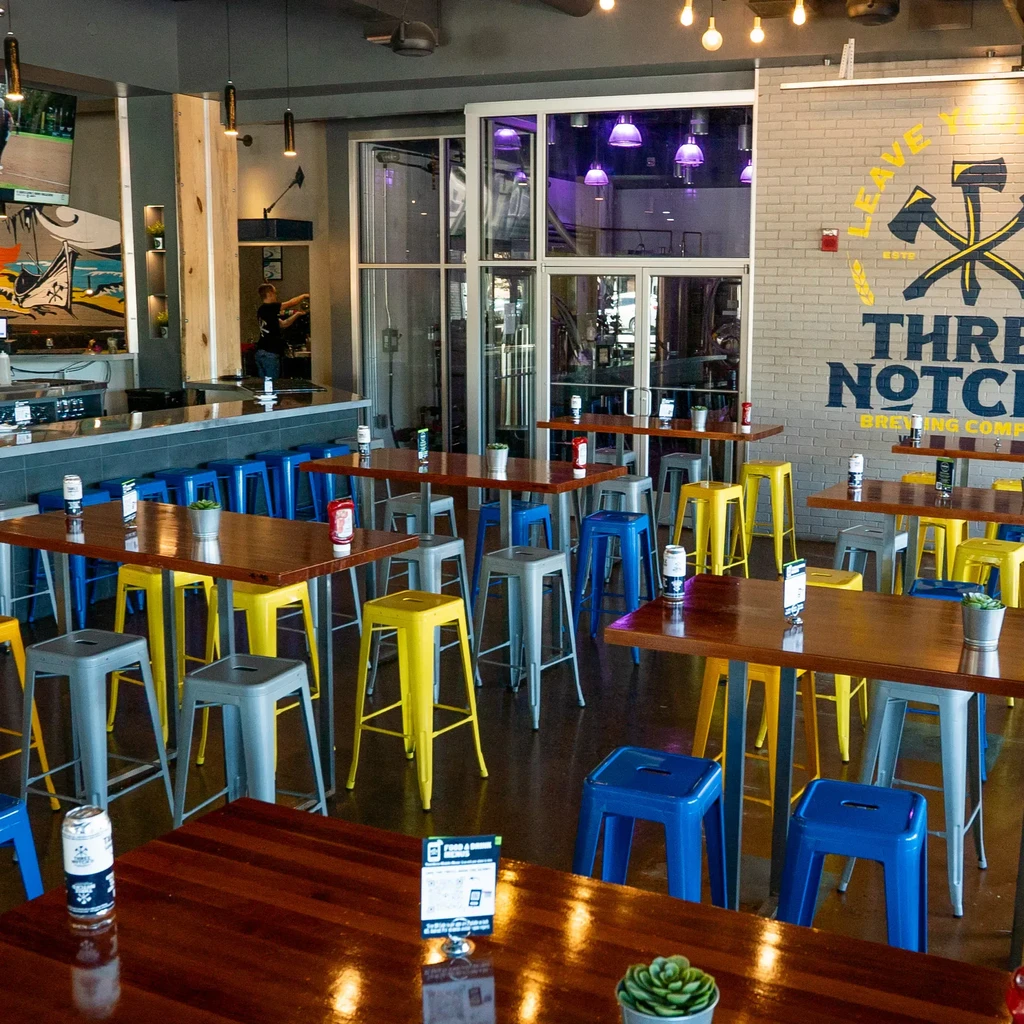 Three Notch Brewing Co. interior with dining, bar, and purple-lit tanks.