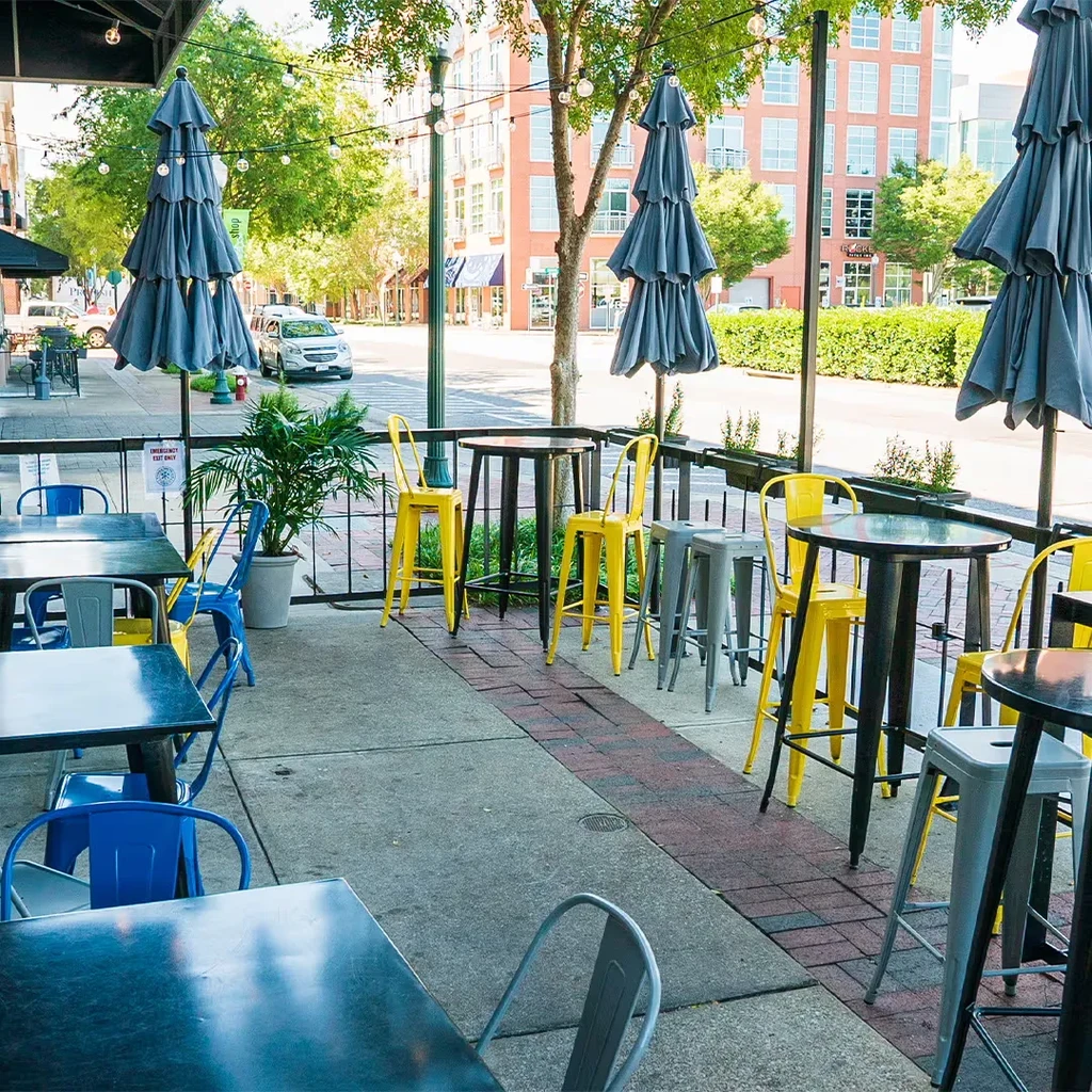 Outdoor restaurant patio with colorful chairs, umbrellas, and string lights.