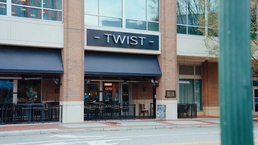Exterior of TWIST restaurant: brick building, outdoor patio, 'OPEN' sign.