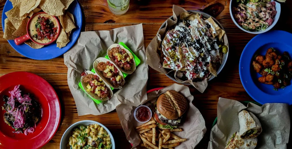 Overhead view of diverse casual dishes and drinks on a wooden table.