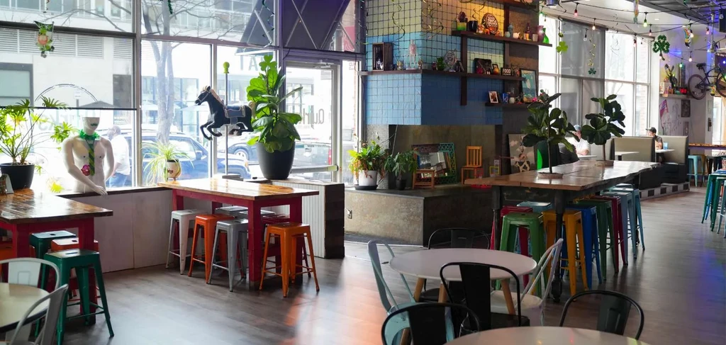 Vibrant, eclectic restaurant interior with colorful seating, plants, and unique decor.