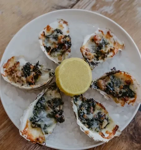 Six gratinéed oysters on the half shell with lemon on ice.