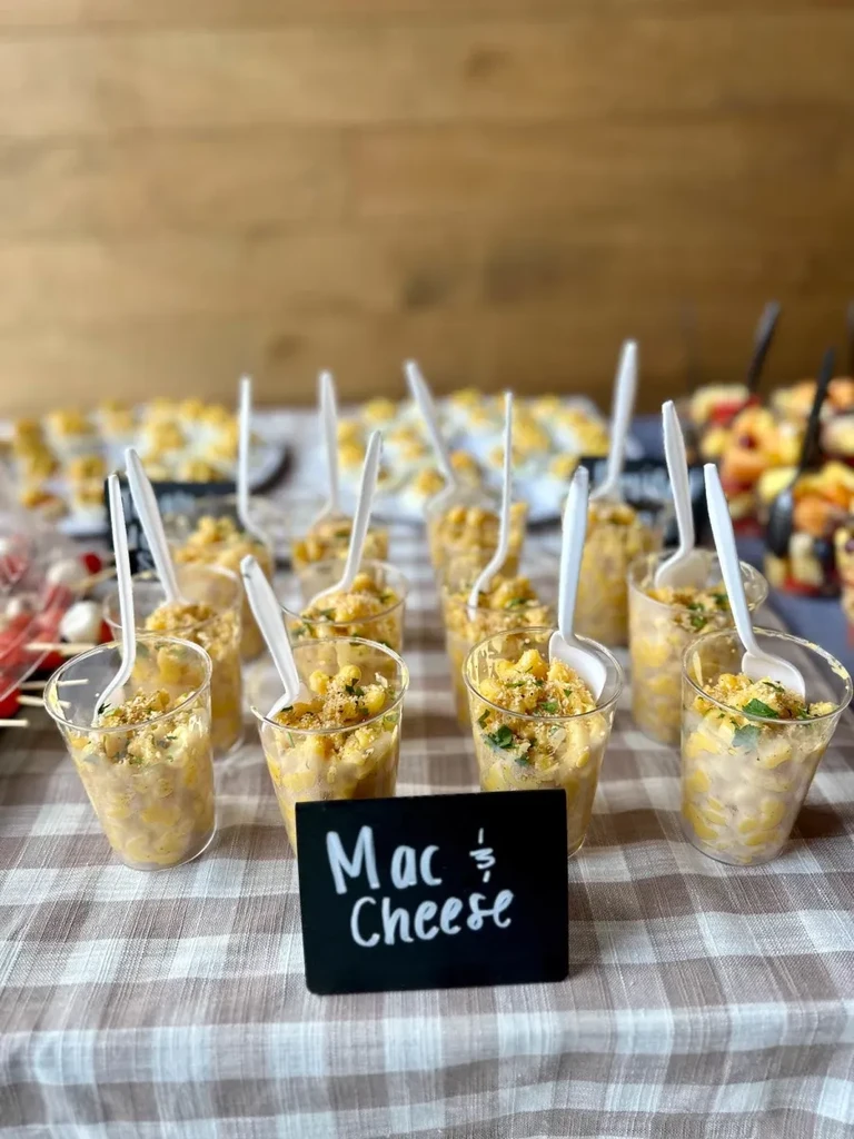 Individual mac and cheese in cups with spoons and a sign.