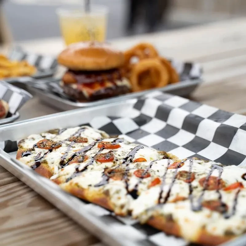 Sliced flatbread pizza with melted cheese, tomatoes, and balsamic glaze.
